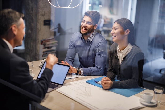 Happy couple sitting at a bank desk, receiving financial advice from a bank advisor